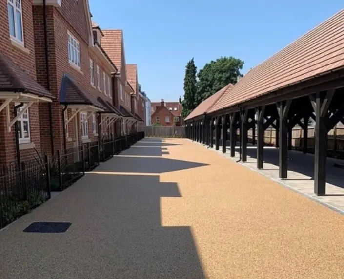 A quiet residential area with red-brick houses and a foreground that has a smooth, light-brown resin pathway.