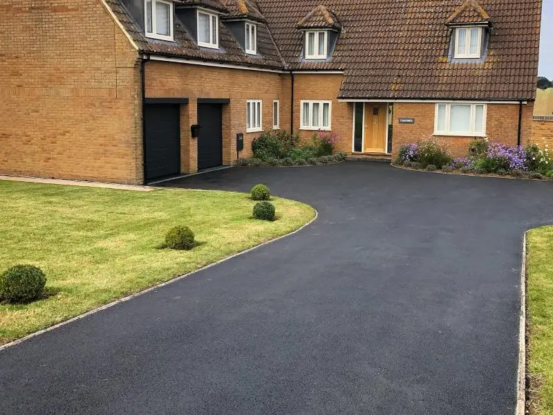 A spacious brick house with a gabled roof features a newly paved driveway.