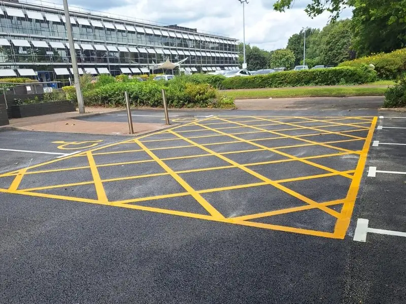 A car park with freshly painted yellow crosshatch lines marks a no-parking zone.